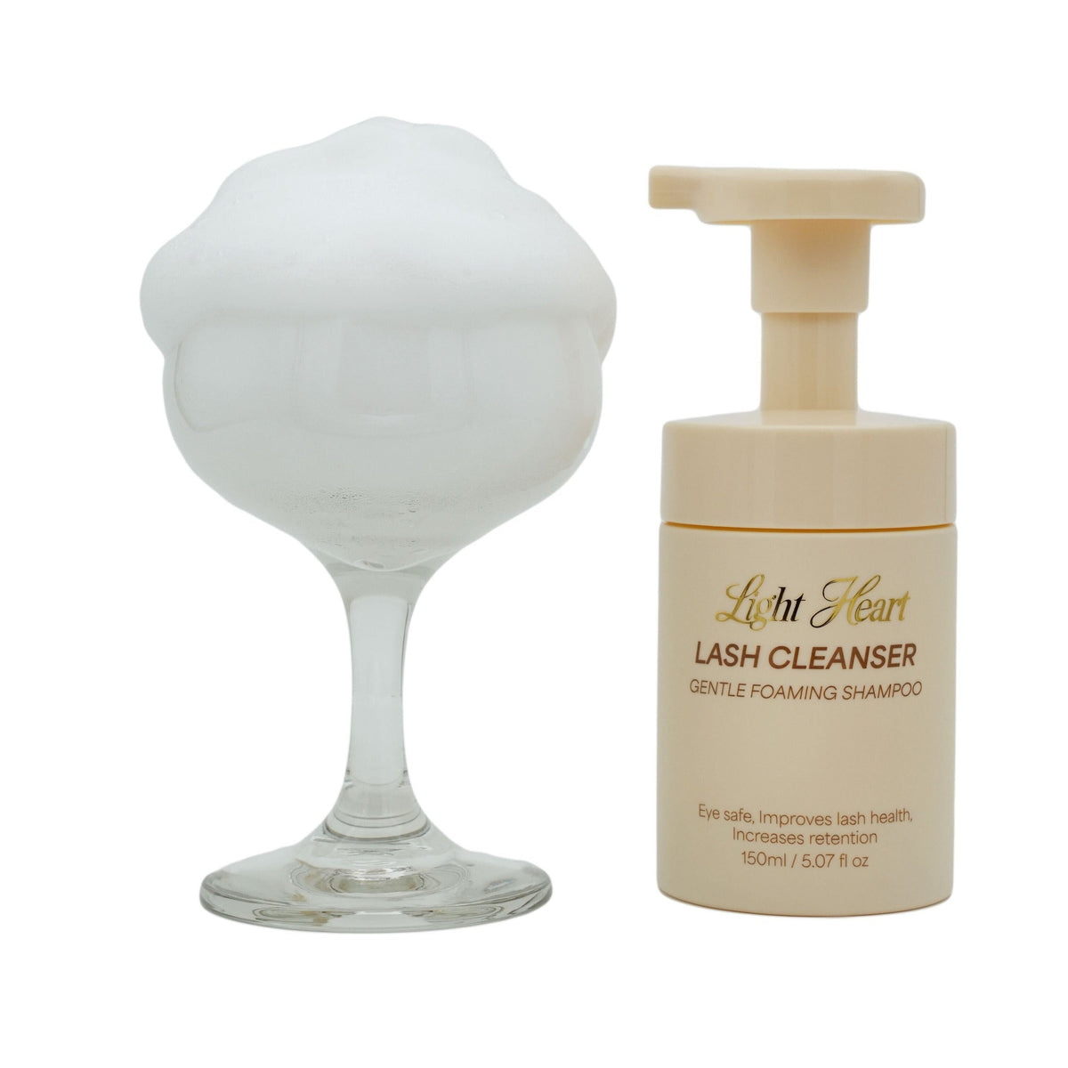Light Heart Beauty Gentle Foaming Lash Cleanser bottle next to a glass filled with thick white cleansing foam